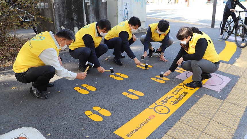 횡단보도 앞 도로에 노란발자국을 설치하는 직원들
